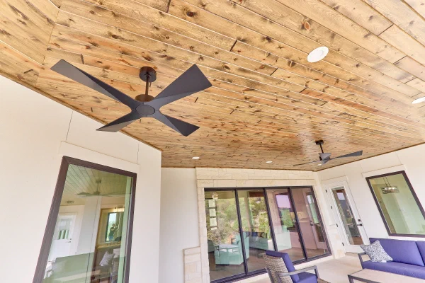Knotty pine porch ceiling with matte black ceiling fans, recessed lighting, and black-framed sliding doors