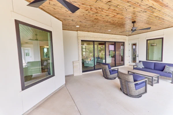 Outdoor living area with wicker seating, limestone accents, and a tongue-and-groove wood ceiling