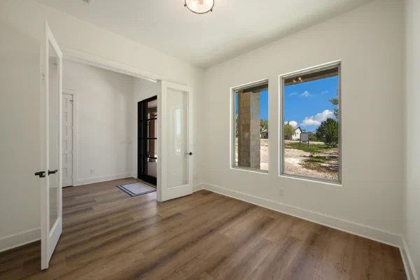 Home office with glass French doors and two windows facing the stone front porch columns