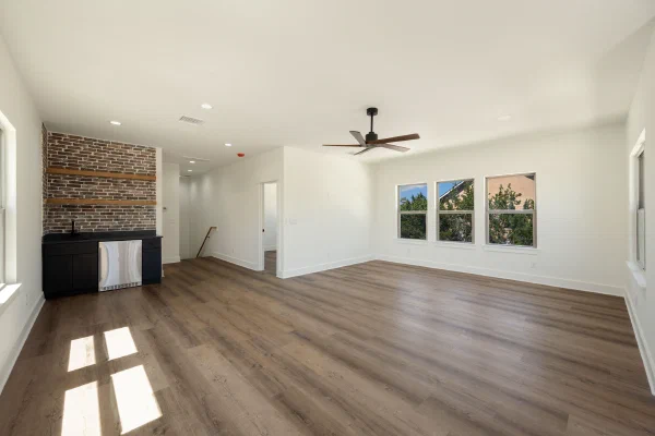 Game room with wet bar, brick accent wall, floating wood shelves, and stainless beverage fridge
