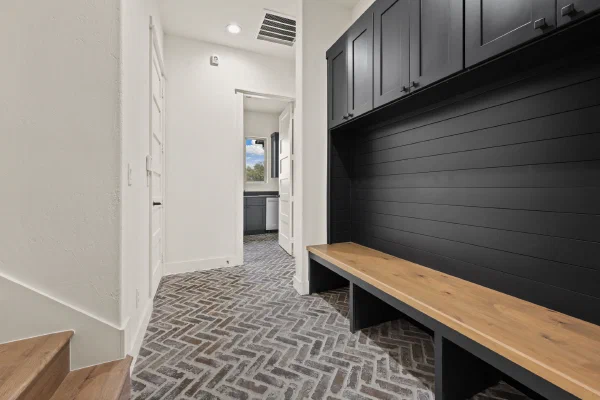 Mudroom hall with herringbone brick pavers, black shiplap drop zone, and white oak bench by the stairs
