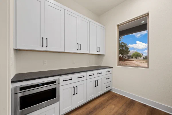 Butler's pantry with white shaker cabinetry, honed black granite counters, and a built-in microwave drawer