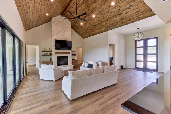 Great room with vaulted knotty pine ceiling, limestone fireplace, and orb chandelier over the iron-door entry
