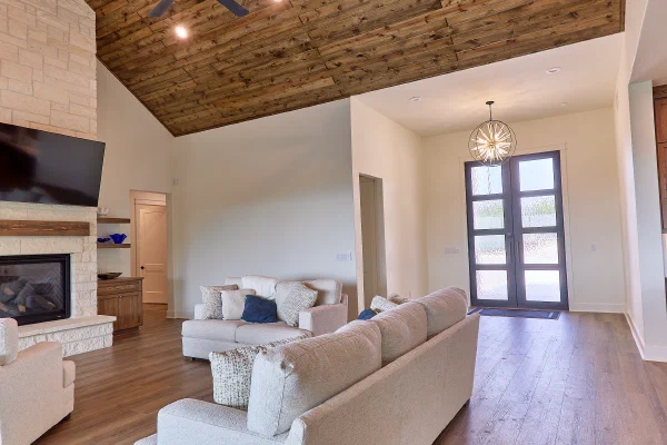 Great room with pine plank ceiling, entry chandelier, and full-light double doors with obscured glass
