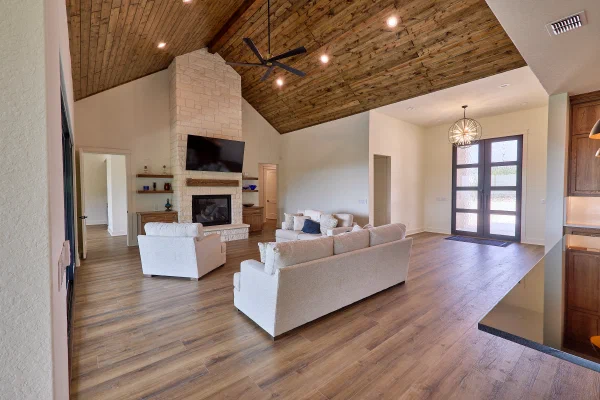 Living room with sliding glass wall opening to a covered patio and sweeping Texas Hill Country views