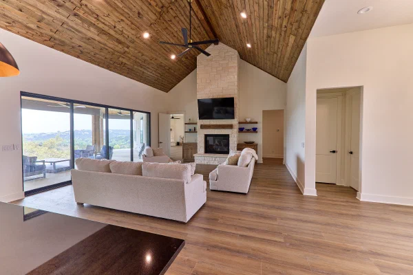 Fireplace wall with white Austin stone chimney, timber mantel, floating shelves, and oak media cabinets