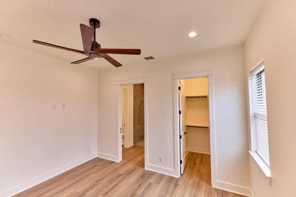 Guest suite in a custom home with ensuite tiled shower, walk-in closet, and wide plank flooring