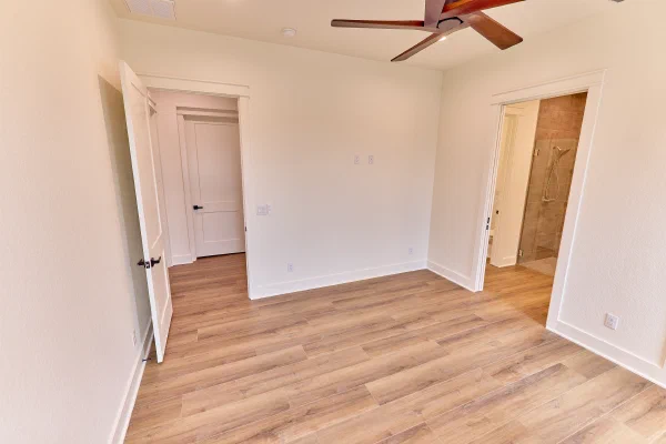 Bedroom with five-blade wood ceiling fan, crisp white trim, and ensuite bath with walk-in tiled shower