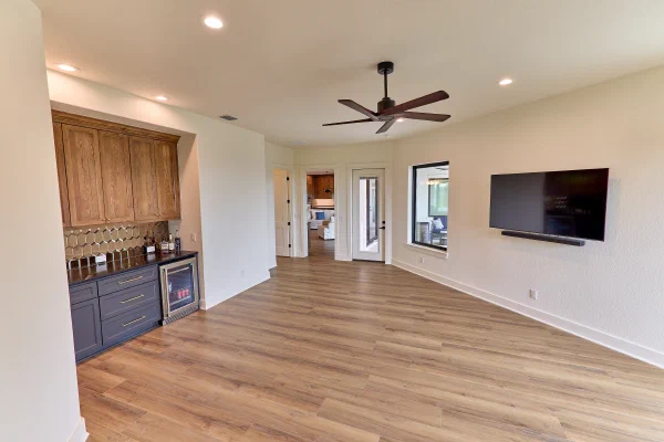 Game room with wet bar, oak uppers over navy cabinets, beverage fridge, and wall-mounted TV