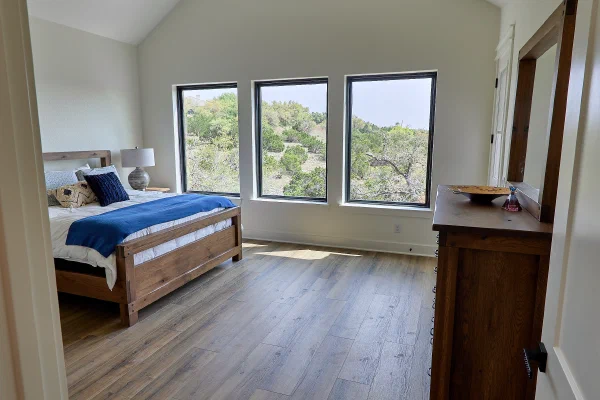 Primary bedroom with gabled ceiling, stained beam, walnut ceiling fan, and rustic oak dresser with mirror