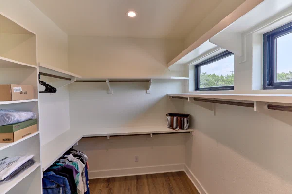 Walk-in closet with wraparound shelving, hanging rods, shoe shelves, and black-framed clerestory windows