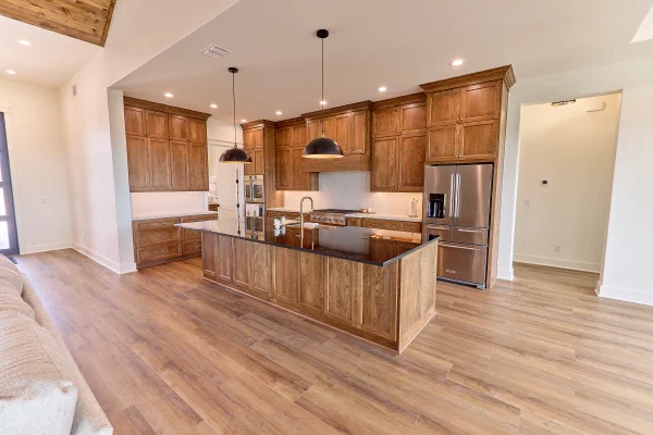 Floor-to-ceiling oak cabinets with gas cooktop, brass hardware and a centered island in gleaming black granite
