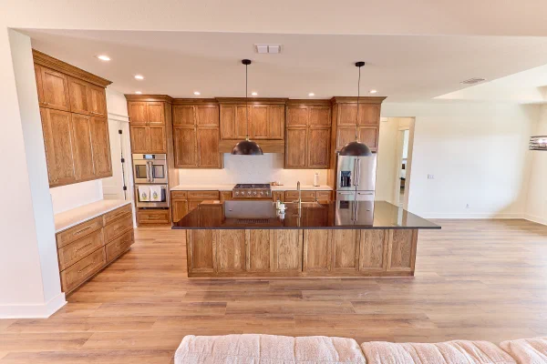Knotty wood plank ceiling and glass entry doors beside an oak island with farmhouse sink and stainless refrigerator
